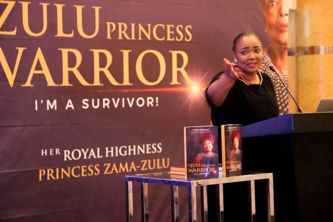 Princess Zama-Zulu speaking beside a display of her book